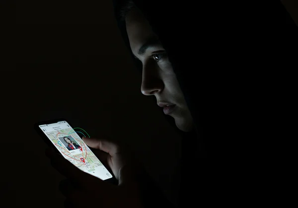 Shadowy figure looking at photo data, illustrating metadata stalking